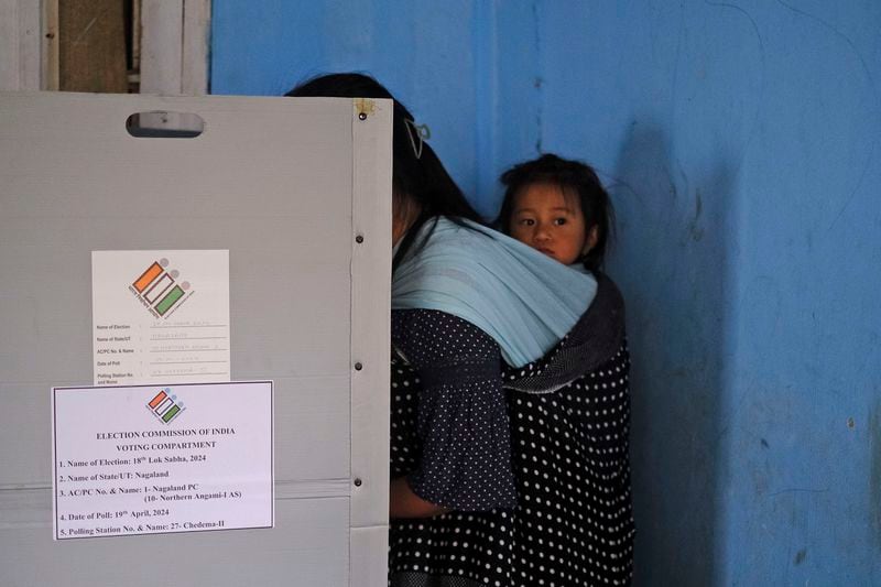 A child looks on as her mother casts her vote during the first round of polling of India’s national election in Chedema village, in the northeastern Indian state of Nagaland, Friday, April 19, 2024. (AP Photo/Yirmiyan Arthur)