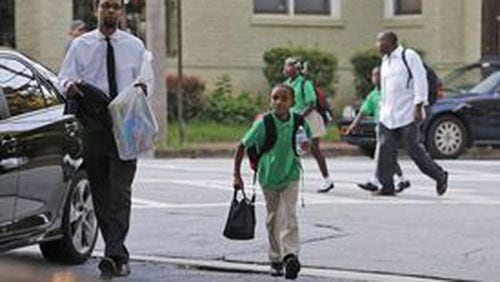 ATLANTA, Aug. 3, 2015 — Bukhari Nuriddin takes his son Sam, 10, to the new Kindezi Schools campus in Atlanta’s Old Fourth Ward neighborhood on opening day. The charter school startup is taking the place of a charter school that was shuttered over the summer after five years of failure. The new operator, who met with success at the first Kindezi campus across town, has high hopes for this new elementary school, near a park frequented by the homeless. BOB ANDRES / BANDRES@AJC.COM