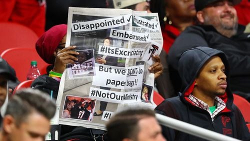 111821 Atlanta: A disappointed, frustrated, embarrassed Falcons fan covers her face with a newspaper as her team falls 25-0 to the Patriots in a NFL football game on Thursday, Nov. 18, 2021, in Atlanta.    “Curtis Compton / Curtis.Compton@ajc.com”
