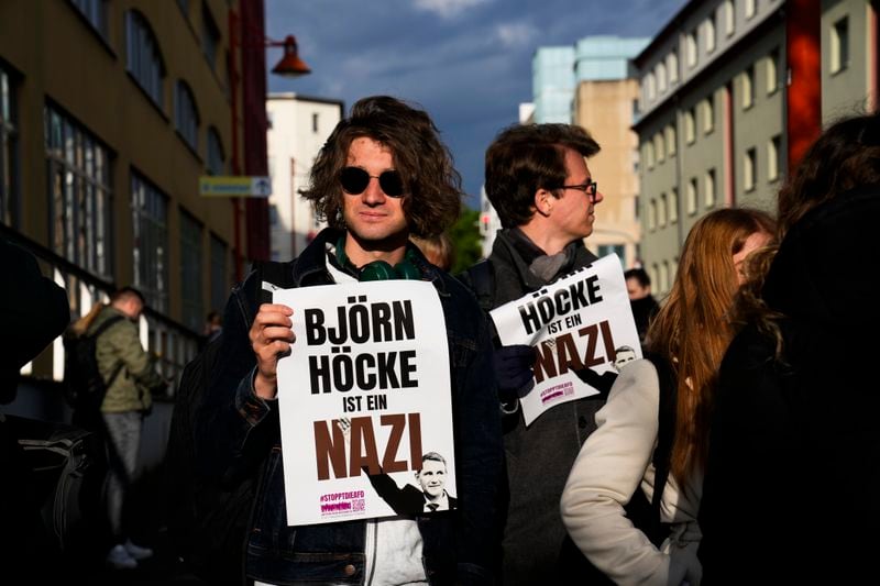 Protestors hold a poster reading 'Bjoern Hoecke is a nazi' outside the state court in Halle, Thursday, April 18, 2024. Bjoern Hoecke, goes on trial at the state court in Halle on charges related to his alleged use in a 2021 speech of a slogan used by the Nazis' SA stormtroopers. (AP Photo/Ebrahim Noroozi, Pool)