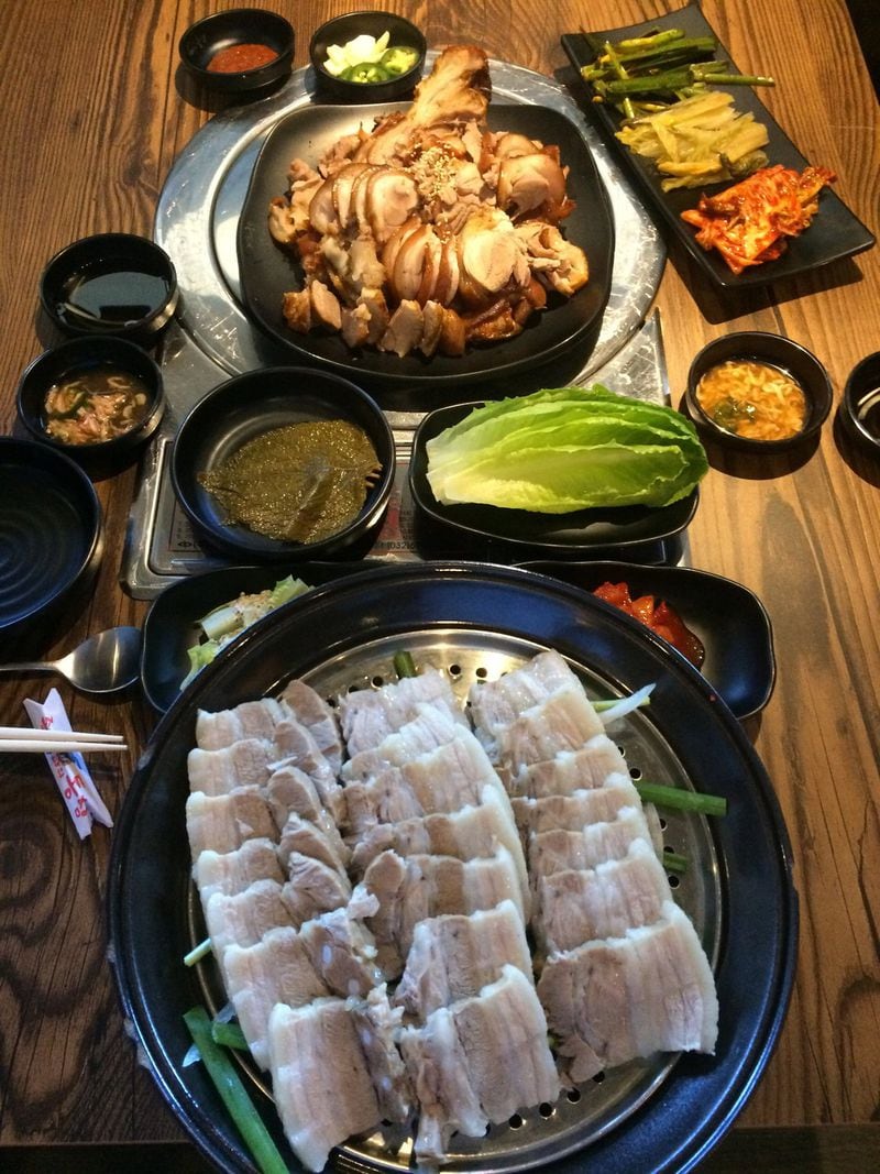 The combination of pig trotter (jokbal) and pork belly wraps (bossam) at Jok Ga A Dong Chim in Duluth comes with a full complement of side dishes (banchan). CONTRIBUTED BY WENDELL BROCK