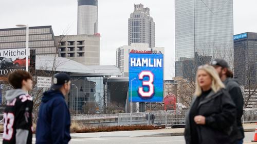 Fans walk by a Damar Hamlin sign in downtown Atlanta Sunday, January 8 as they head to Mercedes-Benz Stadium for the Falcons' season finale against the Bucs.