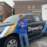 John Lynn, a ShowerUp volunteer, poses with a shower truck and trailer. Lynn is part of a nonprofit network that offers shower services to people living on the streets of Chattanooga, TN. (Photo Courtesy of Mark Kennedy)