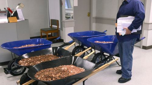 Nick Stafford waits for his number to be called Wednesday, Jan. 11, 2017, as he stands beside of 5 wheelbarrows full of change, mostly pennies, at the DMV in Lebanon, Va. Stafford was paying the sales tax on two cars that he was titling. Stafford had paid $165 to file three lawsuits in Russell County General District Court: two against specific employees at the Lebanon DMV and one against the DMV itself., which means he spent $1,005 to get 10 phone numbers and the satisfaction of delivering 300,000 pennies. Not to mention the nearly $3,000 he paid the DMV for the cars. (David Criggeru/The Bristol Herald-Courier via AP)