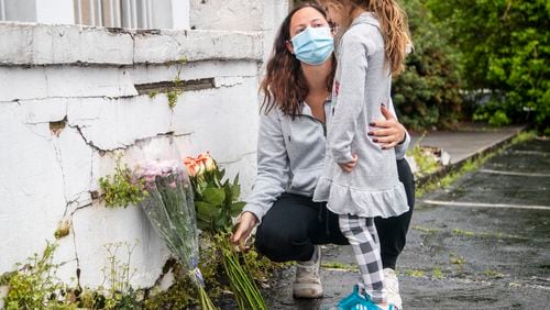 Mallory Rahman and her daughter Zara place flowers near a makeshift memorial outside of the  Gold Spa in Atlanta on March 17, 2021. Three women were killed inside the Gold Spa on March 16,  and another woman was found dead that same night at Aromatherapy Spa across the street.  (Alyssa Pointer / Alyssa.Pointer@ajc.com)
