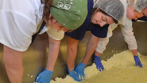 June 6, 2017 — As the whey is drained from the curds, everybody gets into the act of pulling the curds to the sides of a large vat at CalyRoad Creamery in Sandy Springs. Left to right: Creamery owner Robin Schick, cheese-maker Margout Abatto, and intern Peyton Ryan. (Chris Hunt/Special)
