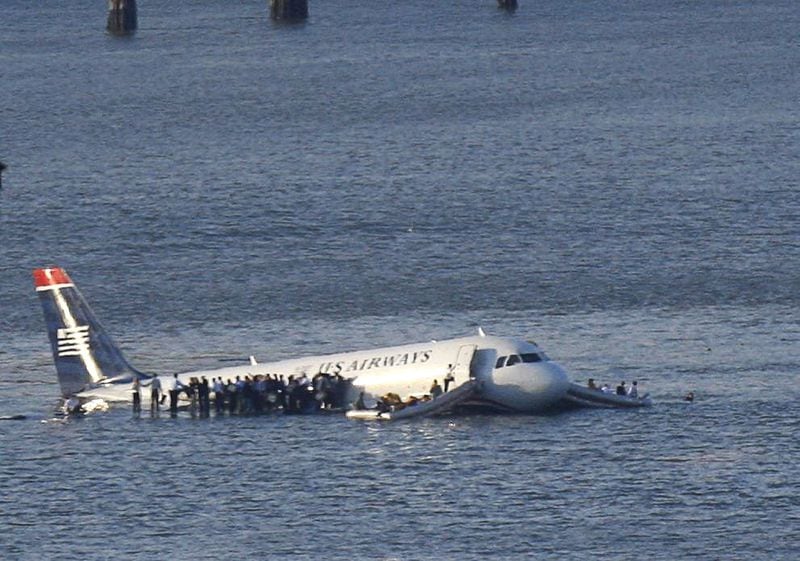 Passengers stand on the wings of a U.S. Airways plane as a ferry pulls up to it after it landed in the Hudson River in New York, January 15, 2009. REUTERS/Brendan McDermid