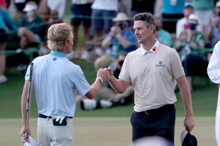 April 10, 2021, Augusta: Xander Schauffele, left, and Justin Rose give each other a fist bump as they finish their third round on the eighteenth green during the Masters at Augusta National Golf Club on Saturday, April 10, 2021, in Augusta. Curtis Compton/ccompton@ajc.com