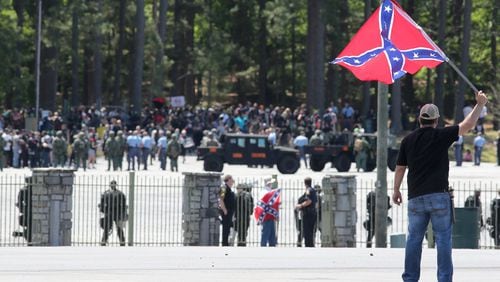 Joseph Andrews, one of a small group with the Rock Stone Mountain rally, waves a confederate battle flag towards a mass of counter-protesters more than 100 yards away at Stone Mountain Park on Saturday afternoon April 23, 2016 where a white power protest and two counter protests were scheduled.