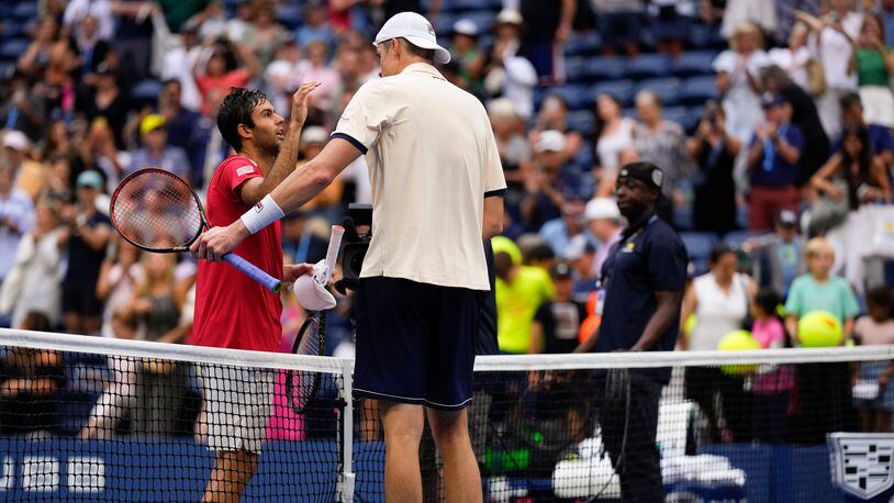 John Isner, right greets Facundo Diaz Acosta at the net after winning their first-round match during the U.S. Open tennis championships, Tuesday, Aug. 29, 2023, in New York. (AP Photo/Manu Fernandez)