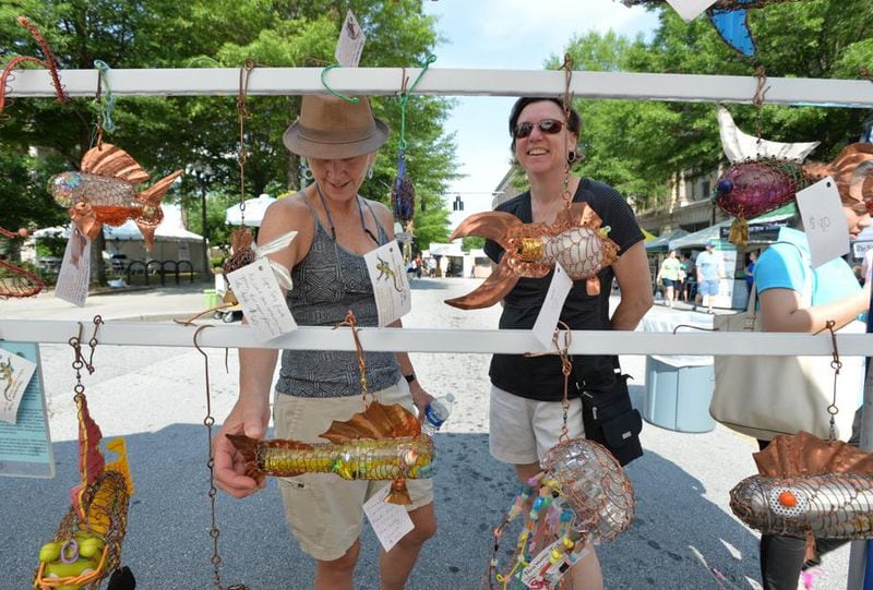 Joan Crumpler (left) and Melinda Brewer, both of Decatur, check out sculptures by Adam and Elissa Newman with Newmanic Tribe during the Decatur Arts Festival 2014 on Saturday, May 24, 2014.