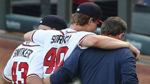 Atlanta Braves manager Brian Snitker helps starting pitcher Mike Soroko off the field after he suffered a torn right Achilles’ tendon and will miss the rest of the season during the third inning against the New York Mets in a MLB baseball game on Monday, August 3, 2020 in Atlanta.    Curtis Compton ccompton@ajc.com