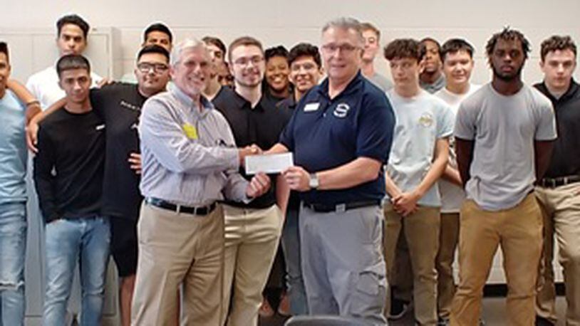 Tom Gardner, the owner of GHD Corporation in Norcross presents a check for $1,000 to Maxwell High Fire Services instructor Gary LaPrad as students look on. COURTESY OF GWINNETT COUNTY PUBLIC SCHOOLS