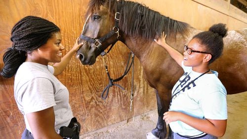 Marsharkia Perry, from the Thomasville Center of Hope Boys and Girls Club, meets her horse Magnum after teaming up with her mentor officer Rackella Johnson at the Atlanta Police Department Mounted Patrol while officers engage children through a mentoring program to strengthen youth-police relations on July 13, 2016, in Atlanta. CURTIS COMPTON / CCOMPTON@AJC.COM