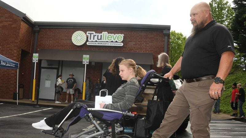 Sydney Wages, 19, (left) and her dad, Jim Wages, (right) both of Dallas, Ga., are at Trulieve Medical Marijuana Dispensary in Marietta on Friday April 28, 2023. Georgia's first medical marijuana dispensaries opened today in Marietta and in Macon. Sydney Wages was the first patient to receive medical marijuana at the dispensary. (Rebecca Breyer for the AJC)