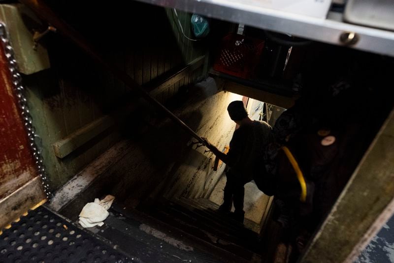 Chef Alex Preciado walks down the steps to the basement to get something for the sports bar while working at The Sports Bra on Wednesday, April 24, 2024, in Portland, Ore. The steps are under a counter in the kitchen. (AP Photo/Jenny Kane)