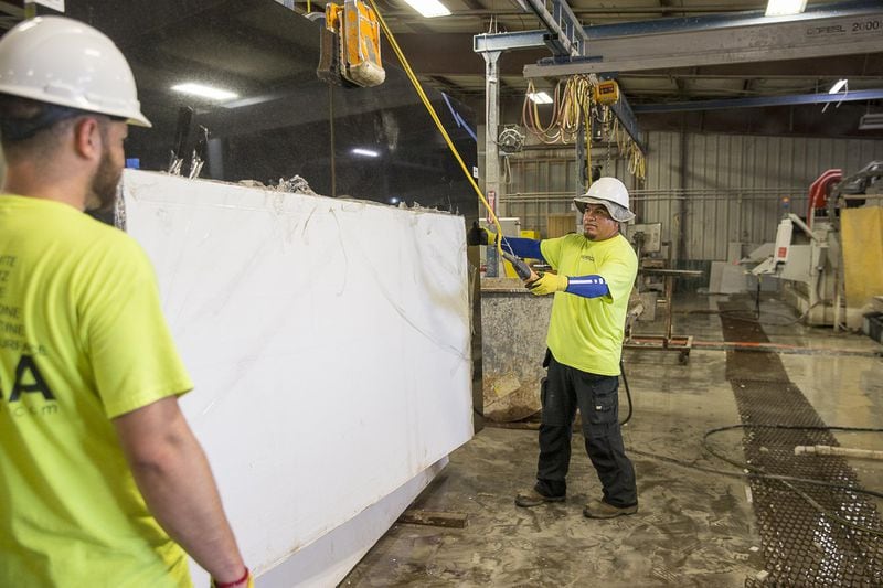 Sawyers Antonio Martinez (right) and Joel Gonzalez handle a slab of quartz at Mega Granite & Marble, Inc. The Newnan company is threatened by duties that make imported quartz harder to get and much more expensive. (Alyssa Pointer/alyssa.pointer@ajc.com)