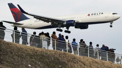 People watch as a Delta Air Lines jet lands at Narita Airport, about an hour east of central Tokyo. AP photo.