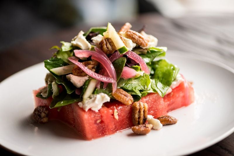 Watuhmelon and Cucumba Salad,  mixed greens tossed ina herb dressing wit spiced pecan, pickled shallots, and goat cheese on a watermelon slice. Photo credit- Mia Yakel.