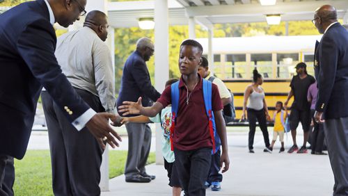 Members of the 100 Black Men of Atlanta  greet students as they arrive for the first day of school at Hamilton E. Holmes Elementary in East Point on Aug. 6.      BOB ANDRES  /BANDRES@AJC.COM