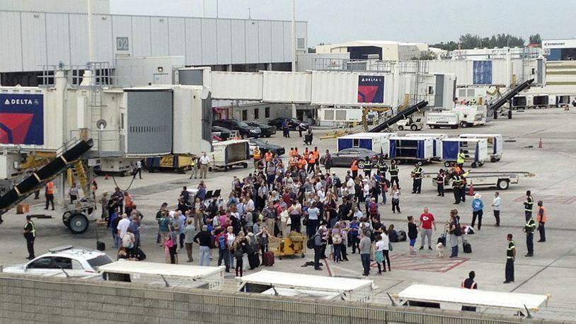People stand on the tarmac at the Fort Lauderdale-Hollywood International Airport after a shooter opened fire inside a terminal of the airport, killing several people and wounding others before being taken into custody, Friday, Jan. 6, 2017, in Fort Lauderdale, Fla. (AP Photo/Wilfredo Lee)
