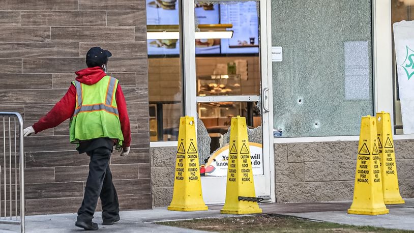 A worker cleans up shattered glass at a McDonald's on Fulton Industrial Boulevard, where a shooting was reported Wednesday morning hours after a separate shooting incident at a Taco Bell just 200 yards away.