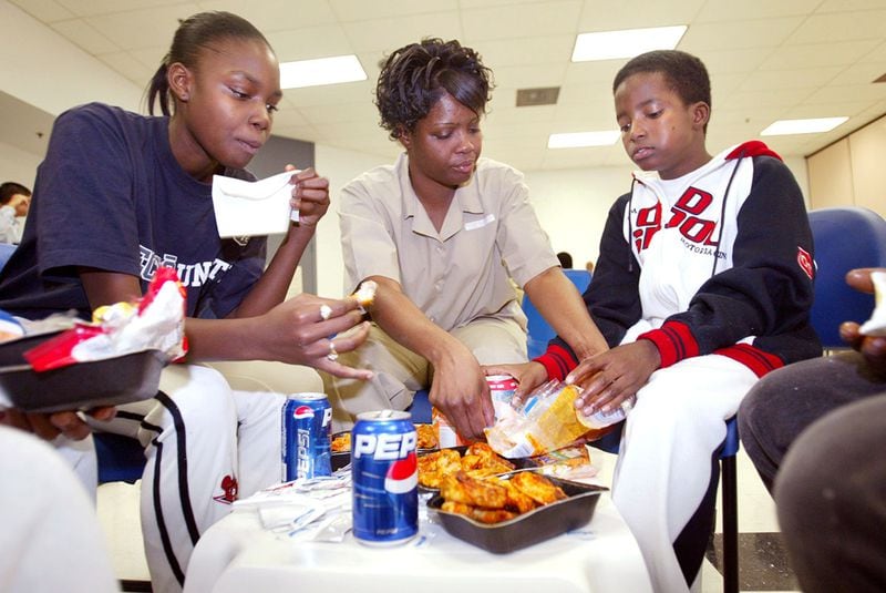 The AJC profiled Marlo Nichols in 2004 and captured this monthly visit by her children, Jamarla (then 14) and Quamarvious (then 10) when Nichols was incarcerated at Washington State Prison in Davisboro. Their meal of microwavable chicken wings, pizza and hamburgers was the only holiday meal they shared that year. (Jenni Girtman / AJC file)