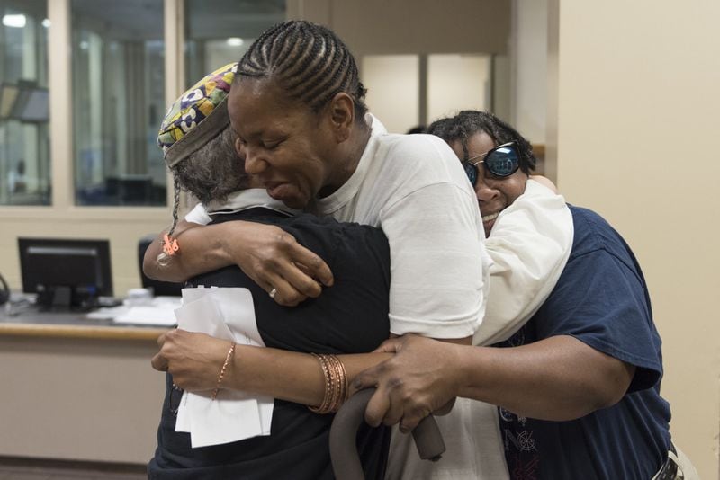 Past Hussain, left, and Cherry Hussain, right, both volunteers with the Black Mama Bailout, hug Donna Hogues, center, who was released from Fulton County Jail Thursday. (DAVID BARNES / DAVID.BARNES@AJC.COM)