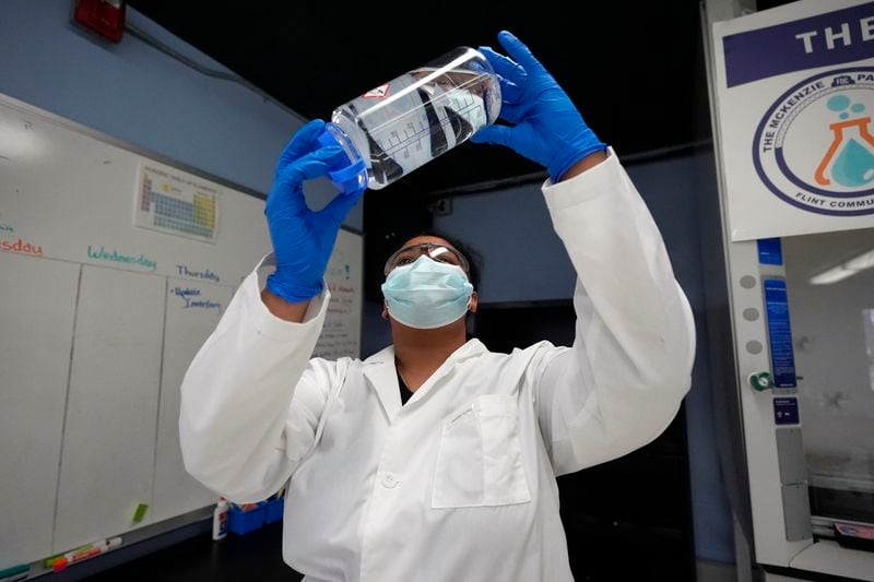 Sima Gutierrez checks the clarity of a water sample at the Flint Community Water Lab, Wednesday, April 3, 2024, in Flint, Mich. The lab, with more than 60 high school and college interns, has provided free water testing for thousands of residents since 2020. (AP Photo/Carlos Osorio)