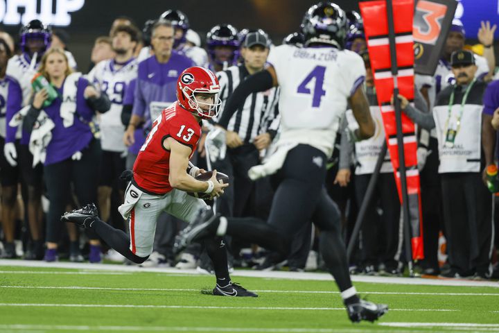 Georgia Bulldogs quarterback Stetson Bennett (13) runs a keeper play against TCU Horned Frogs safety Namdi Obiazor (4) during the first half of the College Football Playoff National Championship at SoFi Stadium in Los Angeles on Monday, January 9, 2023. (Jason Getz / Jason.Getz@ajc.com)