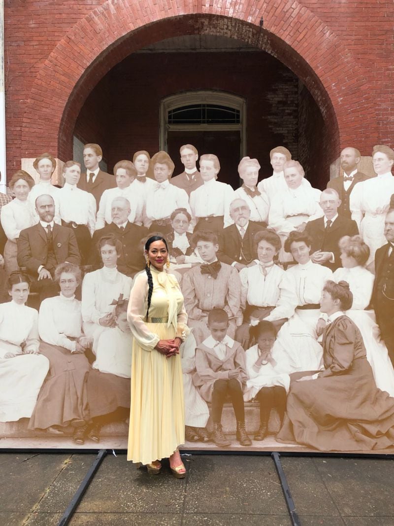 Atlanta Historian Karcheik Sims-Alvarado poses in front of the 17x8 reproduction of the turn of the 20th century photograph of the Atlanta University faculty at Tuesday's unveiling at Morris Brown College.