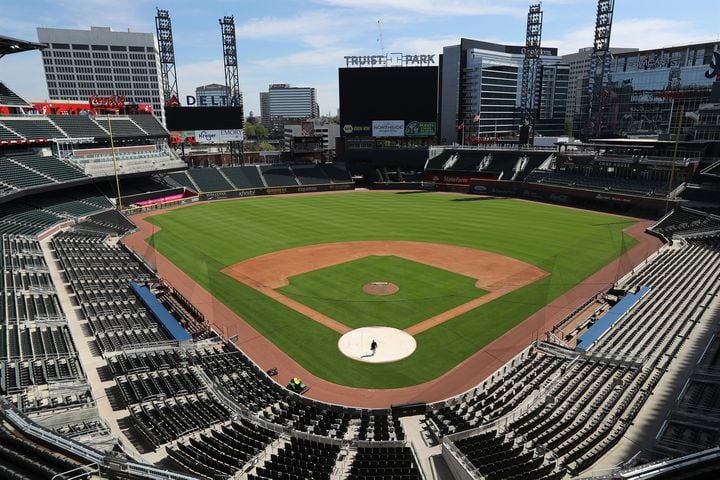 April 1, 2020 Atlanta: The stadium is eerily quiet except for Atlanta Braves field manager Tyler Lenz walking across the covered home plate while maintaining the quality of the field in the team’s newly renamed Truist Park on Wednesday, April 1, 2020, in Atlanta. The Braves were suppose to host their home opener this Friday, but the season’s start was postponed by Major League Baseball because of the coronavirus pandemic. A basic crew is keeping the quality of the field up to playing conditions while no one knows when, or even if, the 2020 season will start, or how long it might last.   Curtis Compton ccompton@ajc.com