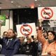 Cobb County residents hold up signs that say "No Rain Tax" in protest of the stormwater utility fee at the Board of Commissioners meeting on Tuesday, March 26, 2024. The board postponed the vote after several hours of public discourse. (Taylor Croft/taylor.croft@ajc.com)