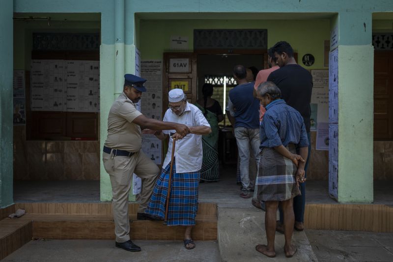 A policeman assists an elderly voter at a polling station during the first round of polling of India's national election in Chennai, southern Tamil Nadu state, Friday, April 19, 2024. Nearly 970 million voters will elect 543 members for the lower house of Parliament for five years, during staggered elections that will run until June 1. (AP Photo/Altaf Qadri)