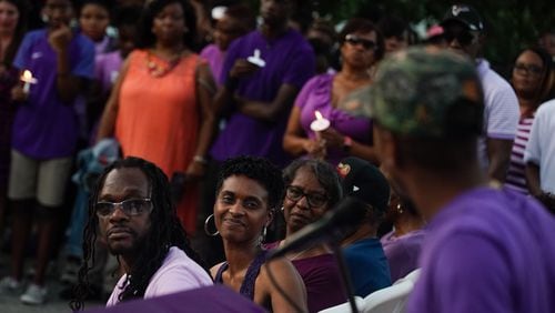 Imani Bell's parents look on as the teen's former coach speaks during Wednesday candlelight vigil.