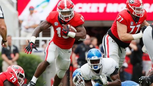 The Bulldogs offensive line supplies the daylight Saturdy and running back Elijah Holyfield makes the most of it. (BOB ANDRES  /BANDRES@AJC.COM)
