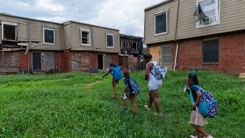 A family living in the Forest Cove Apartments walks to their home from the children's bus stop in August 2022. Atlanta completed the relocation of the condemned complex's residents in October of that year. Now, U.S. Sens. Jon Ossoff of Georgia and Sherrod Brown of Ohio say they will examine whether owners of federally subsidized apartment complexes are being held to account for conditions at their properties. (Arvin Temkar / arvin.temkar@ajc.com)