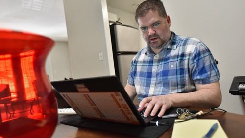 Patrick Hill works on his laptop at his apartment home in Sandy Springs. The CPA is now a full-time employee at Home Depot, but he worked contract jobs for a decade. HYOSUB SHIN / HSHIN@AJC.COM