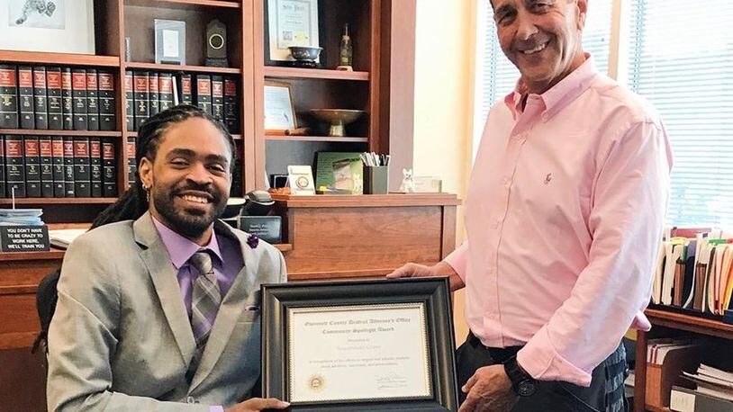 Arquevious “Que” Crane receiving the “community spotlight” award from Gwinnett County District Attorney Danny Porter. Employees of Porter’s office are now raising money to help Crane, a quadriplegic who is a motivational speaker, replace his aging van. VIA GWINNETT DISTRICT ATTORNEY’S OFFICE