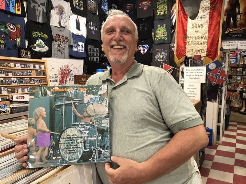 Tom Wright, owner of The Wright Stuff Records & Collectibles in Woodstock, shows off one of his albums: a "Woodstock" album, which features a naked boy. He covers the privates with a Post-It note so as not to offend potential customers. Photo taken Oct. 4, 2018. CREDIT: Rodney Ho/rho@ajc.com