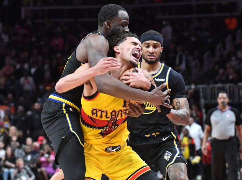 Hawks' guard Trae Young (11) is fouled by Golden State Warriors' forward Draymond Green (left) at the end of the 4th quarter in an NBA basketball game at State Farm Arena on Friday, March 25, 2022. Atlanta Hawks won 121-110 over Golden State Warriors. (Hyosub Shin / Hyosub.Shin@ajc.com)