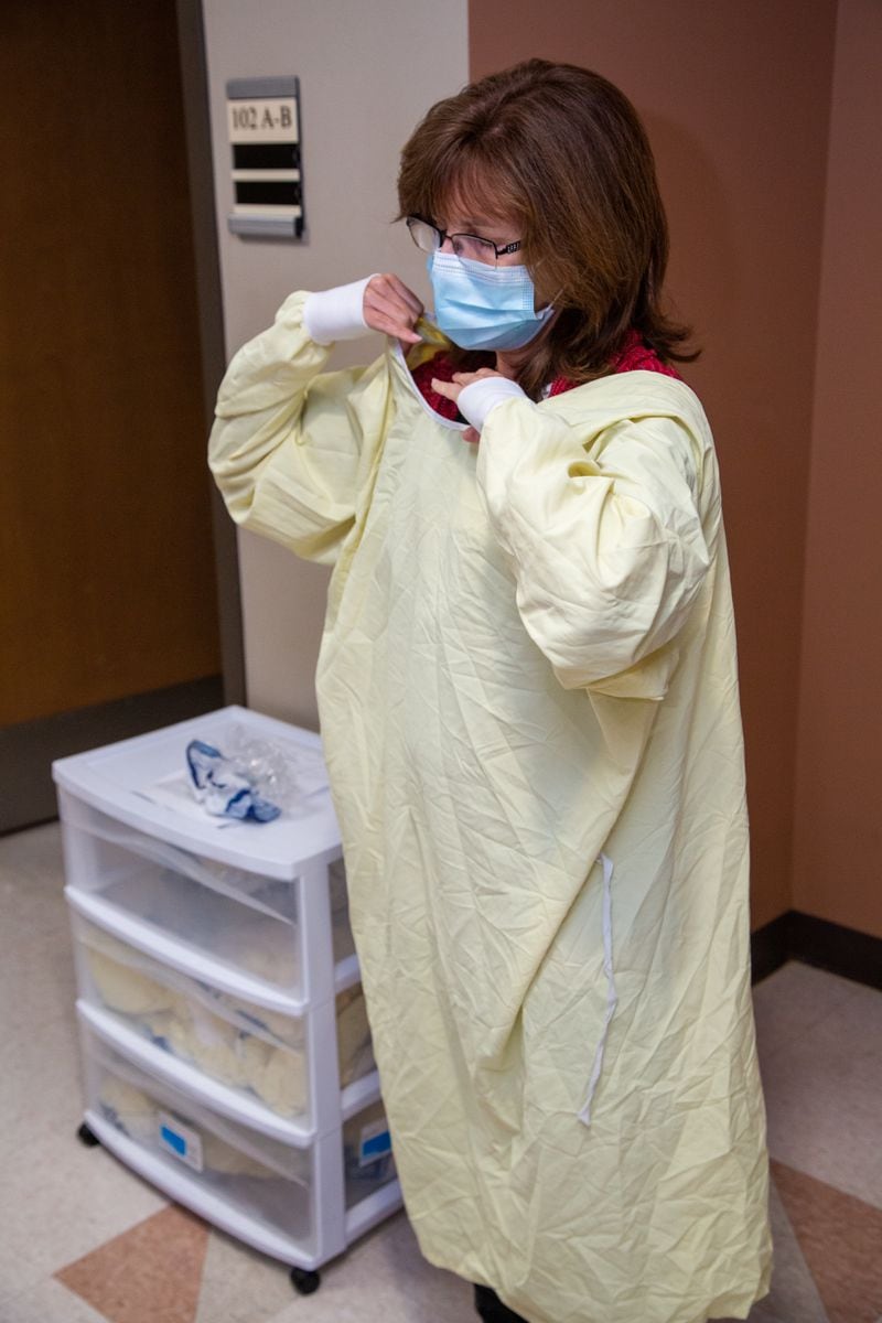 Sandi Thurber dons a PPE gown before visiting a resident at Northside Gwinnett Extended Care Center in Lawrenceville. (Phil Skinner for The Atlanta Journal-Constitution)