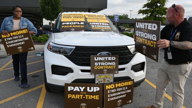 August 4, 2022 Atlanta - Eric Massaro (right) and Aluana Freeman, both members of Teamsters and UPS employees, hold a sign in the employee parking lot after holding a contract rally inside UPS SMART Hub in Atlanta on Thursday, August 4, 2022. The Teamsters were holding a contract rally among workers in preparation for negotiations with UPS coming up over the next year. (Hyosub Shin / Hyosub.Shin@ajc.com)