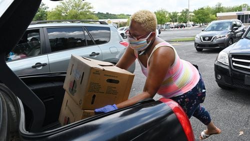 Volunteer Fay Reid loads a car with food at The Gallery at South DeKalb mall on Friday, July 10, 2020, at a food drive organized by DeKalb County Commissioner Larry Johnson.