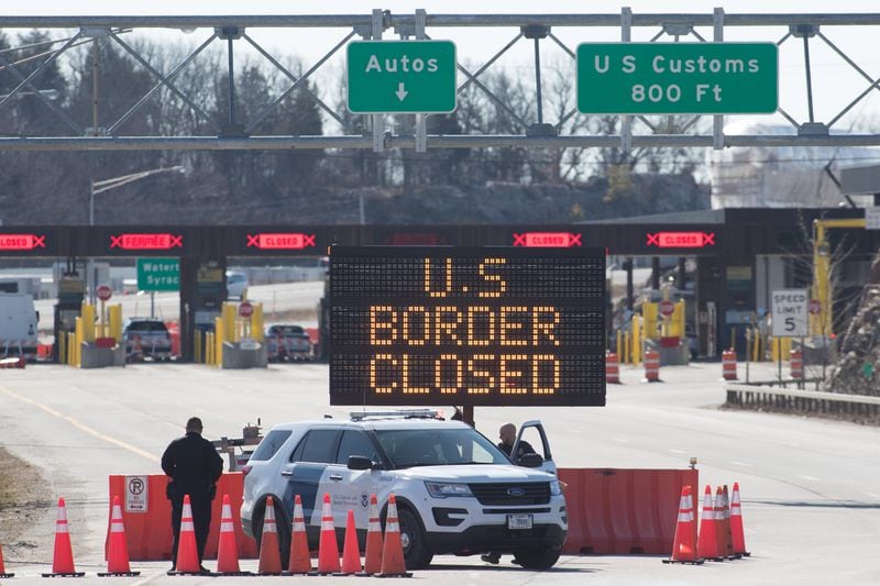 U.S. Customs officers stand beside a sign saying the U.S. border is closed at the Canada border in Lansdowne, Ontario. After more than a year of restrictions, the land borders are opening again starting in November. (Lars Hagberg/TNS)