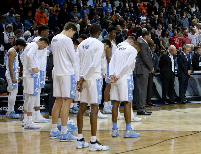 North Carolina team members and fans stand for a moment of silence to honor former UNC radio announcer Woody Durham, who died earlier this week, before the team's NCAA college basketball game against Syracuse in the second round of the Atlantic Coast Conference men's tournament Wednesday, March 7, 2018. in New York. (Chuck Liddy/The News & Observer via AP)