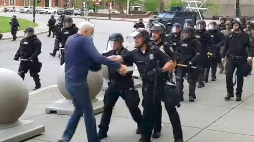 In this image from video provided by WBFO, a Buffalo police officer appears to shove a man who walked up to police Thursday, June 4, 2020, in Buffalo, N.Y. Video from WBFO shows the man appearing to hit his head on the pavement, with blood leaking out as officers walk past to clear Niagara Square. (Mike Desmond/WBFO via AP)