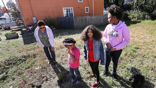 Rosario Hernandez (from left) and her granddaughters Ava Booker, 5, Aniyah Royal, 9, and Aryanna Maymi Booker, 11, look for pieces of slag on the vacant lot next to her home near Mercedes-Benz Stadium on Nov. 25, 2019, in Atlanta. Hernandez discovered slag, a byproduct of smelting, on the property. Her home has shown high levels of lead in the soil. CURTIS COMPTON / CCOMPTON@AJC.COM