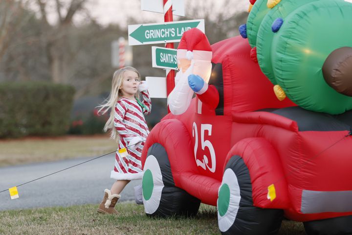 Alayna Jernigan walks around an inflatable Christmas decoration as her grandparents, Renee and Walter Wright, try to take a photo at one of the intersections decorated with candy cane stripes in the town of Santa Claus.
 Miguel Martinez / miguel.martinezjimenez@ajc.com