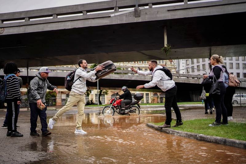 People evacuate from an area flooded by heavy rains, in Porto Alegre, Rio Grande do Sul state, Brazil, Friday, May 3, 2024. (AP Photo/Carlos Macedo)